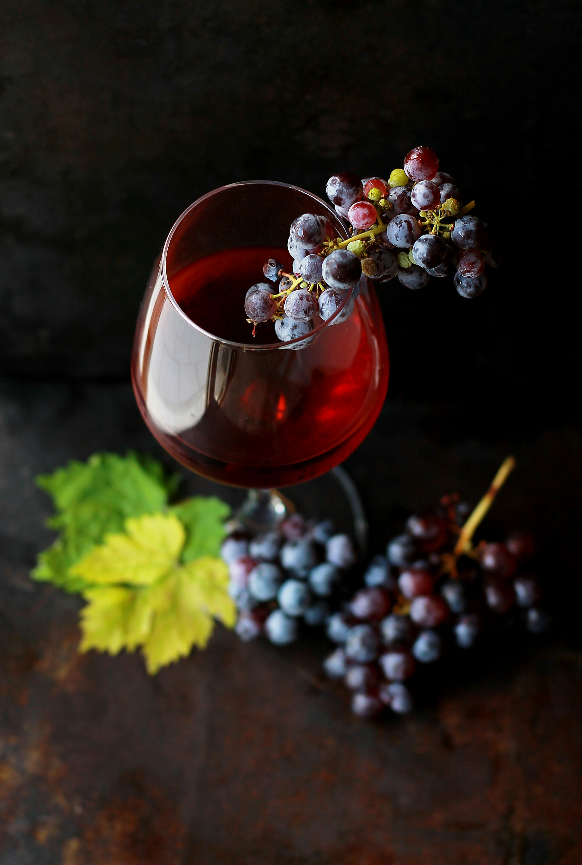 Red wine and fresh grapes against a dramatic dark background